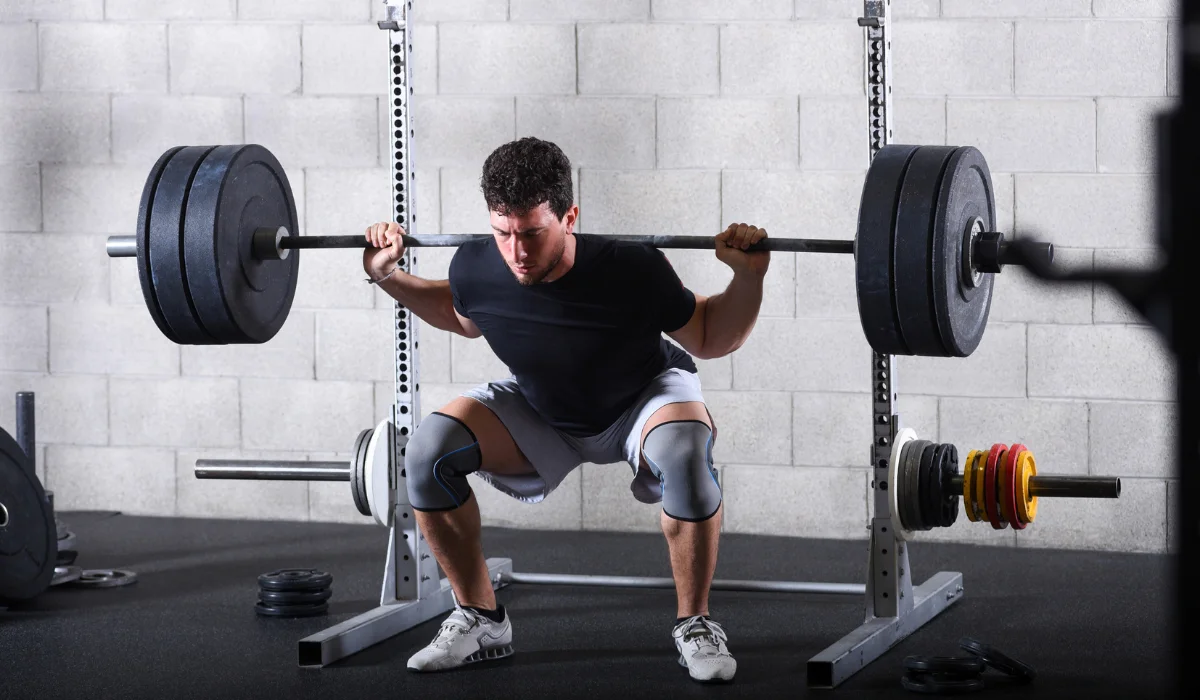 Athletic man doing a squat while lifting a barbell