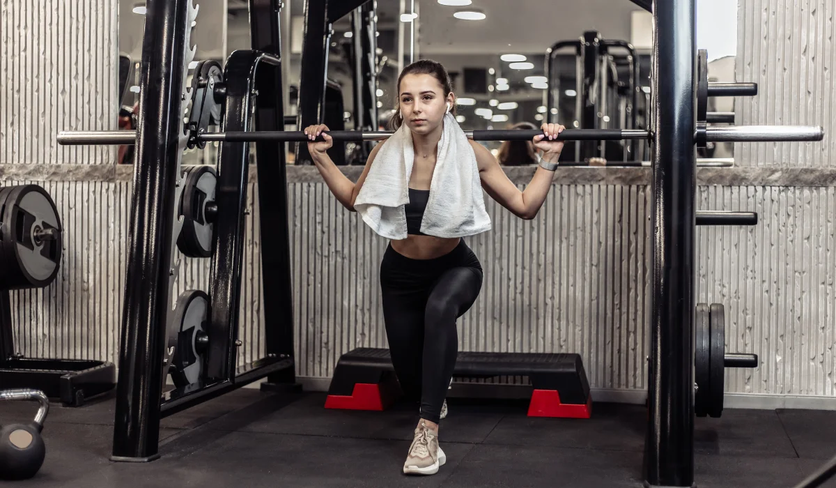 Athletic woman doing a squat using the squat rack