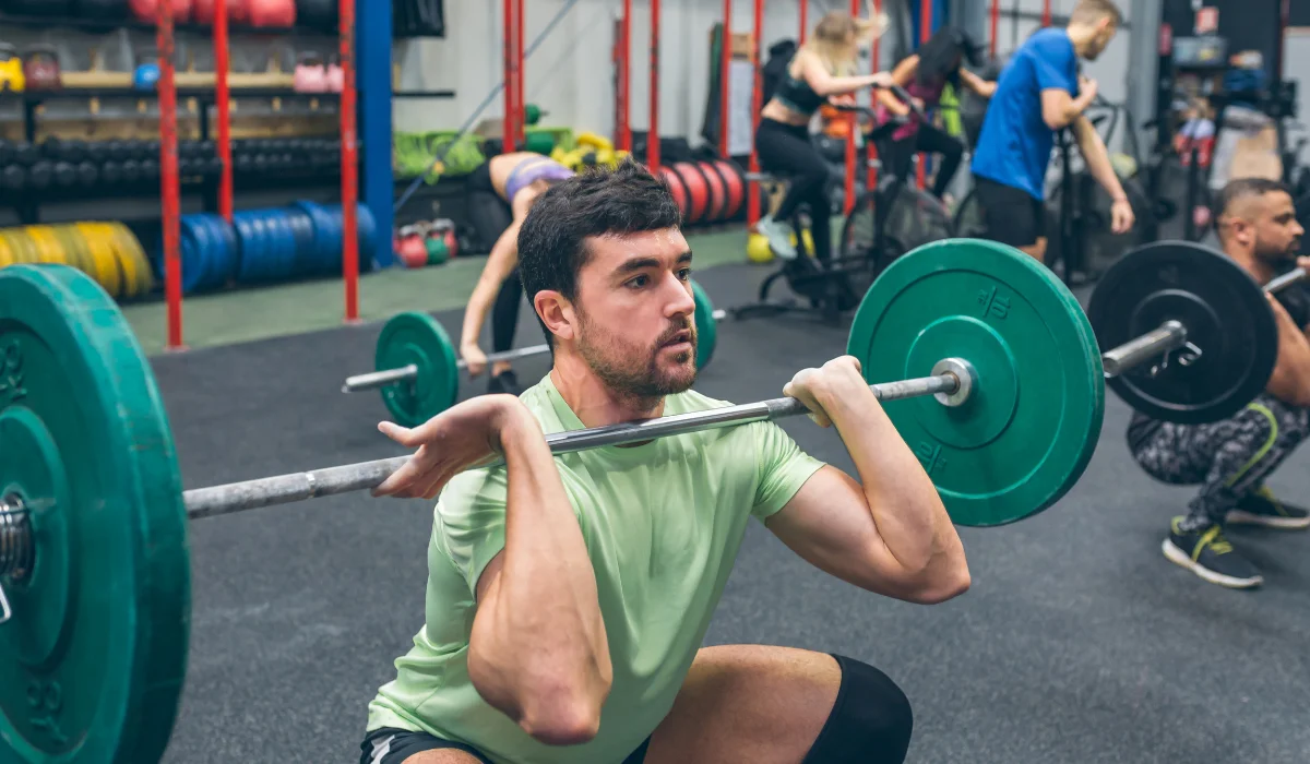 Group of people in the gym lifting a barbell and other workout.